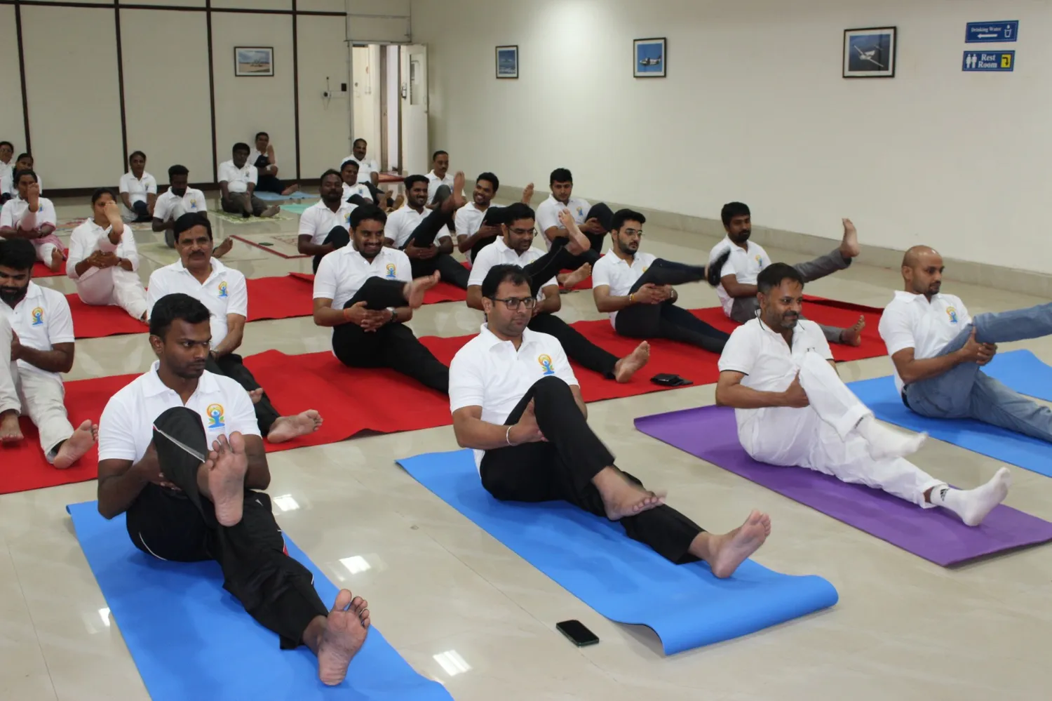 Students in a seated leg-raise stretch on colourful mats