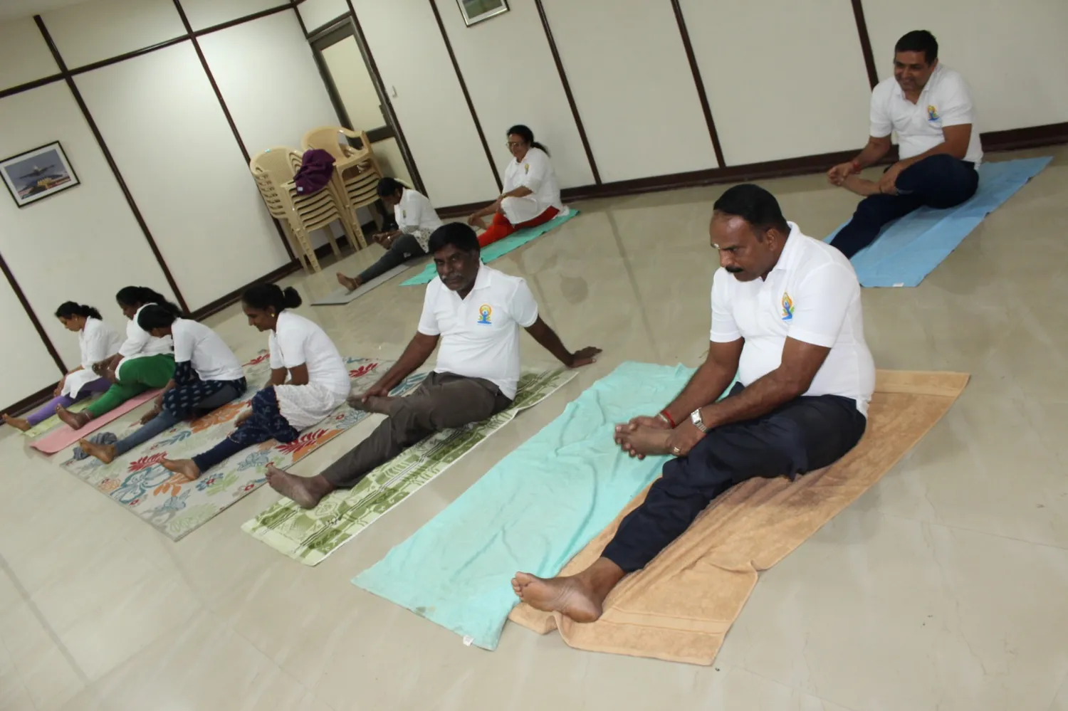 Rows of participants in a seated forward bend on yoga mats