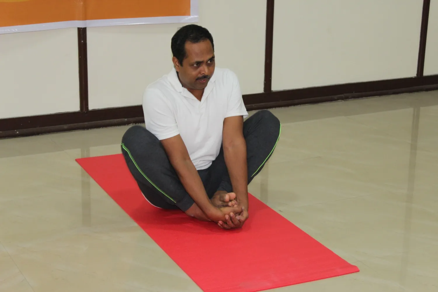 A student in bound-angle (butterfly) pose on a red mat
